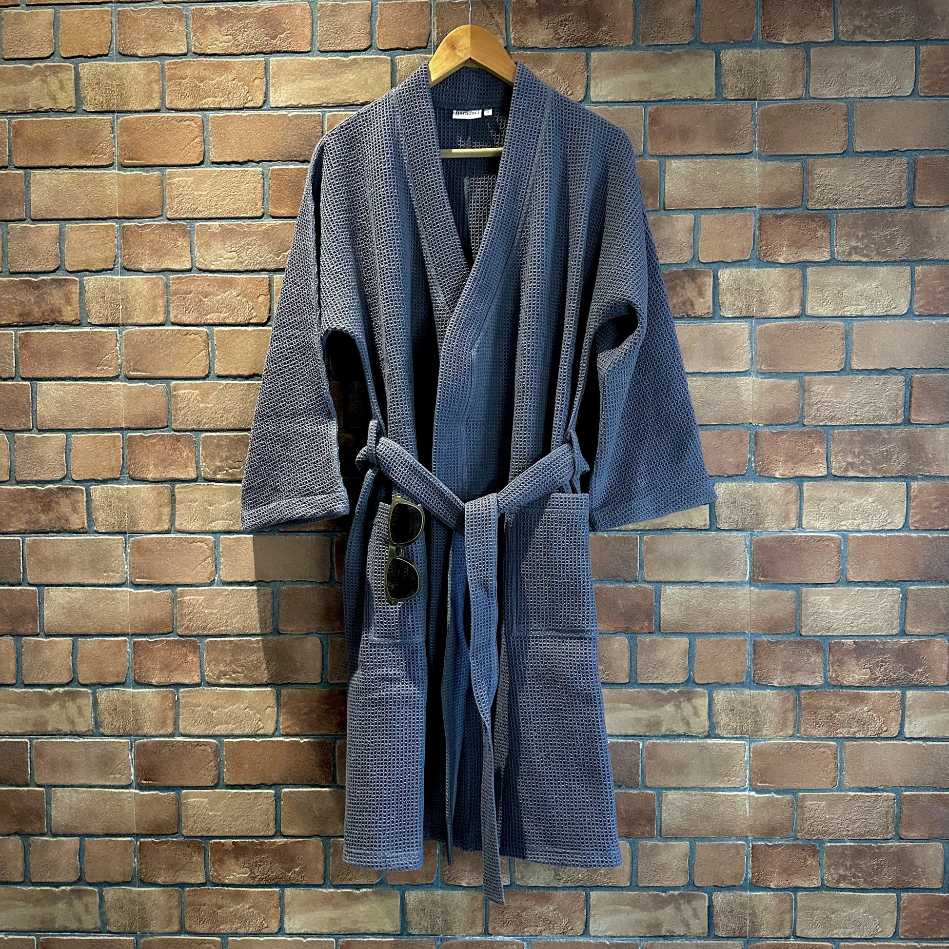"Baradari pure cotton waffle bath robe in cream hanging on rack — full length organic cotton unisex bath robe with belt and pocket"