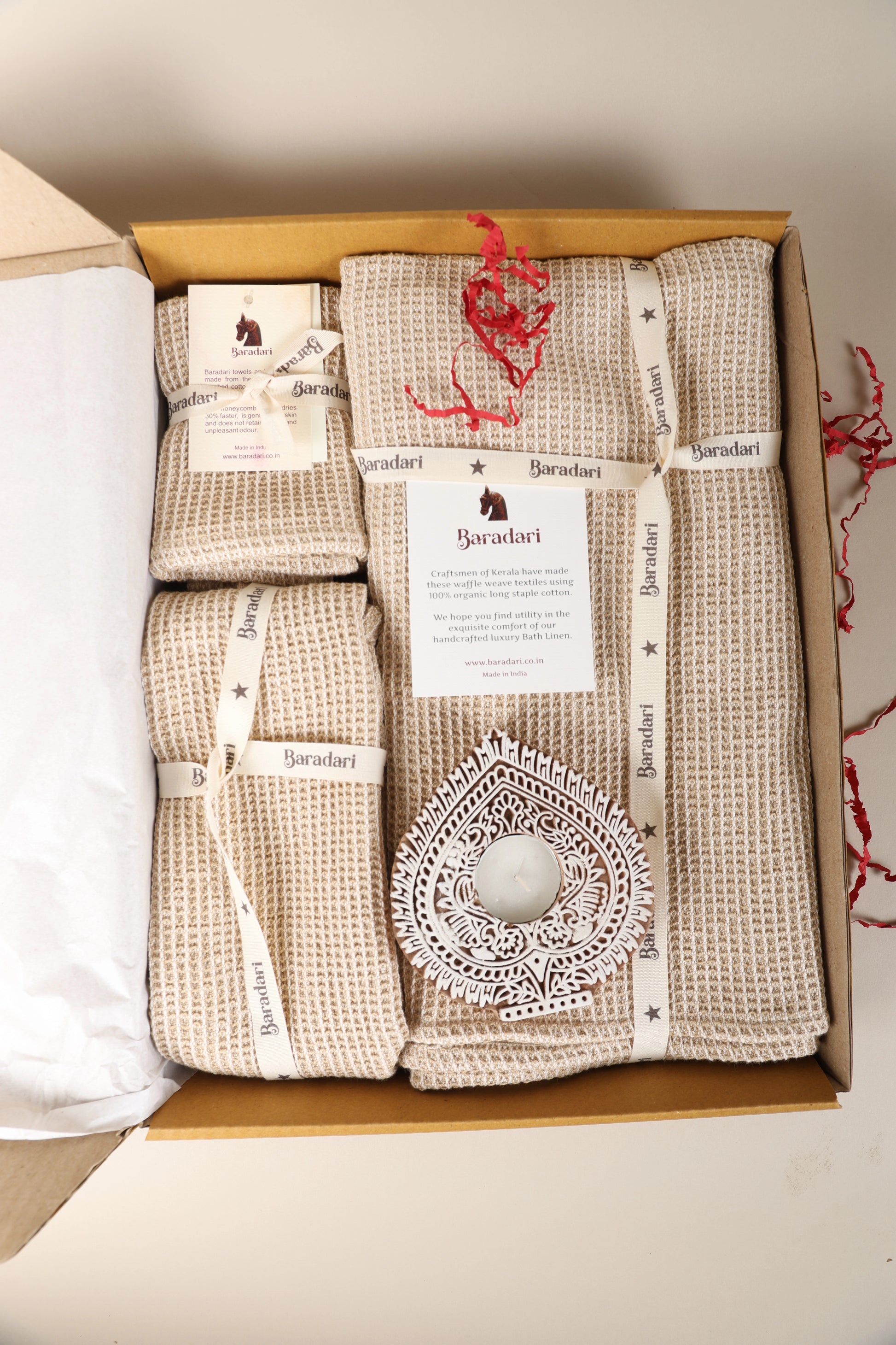 "Baradari gifting hamper with natural beige organic waffle weave bath towels, washcloths, and carved wooden diya tealight holder — festive bath linen gift set by Baradari"