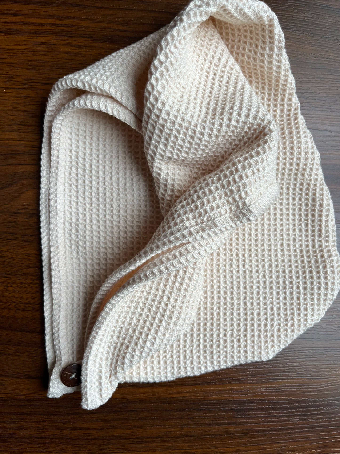 Beige pure cotton waffle shampoo towel   on a wooden surface
